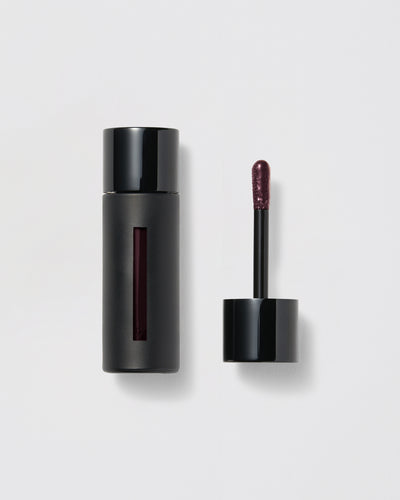Black lip gloss container with applicator on a gray background