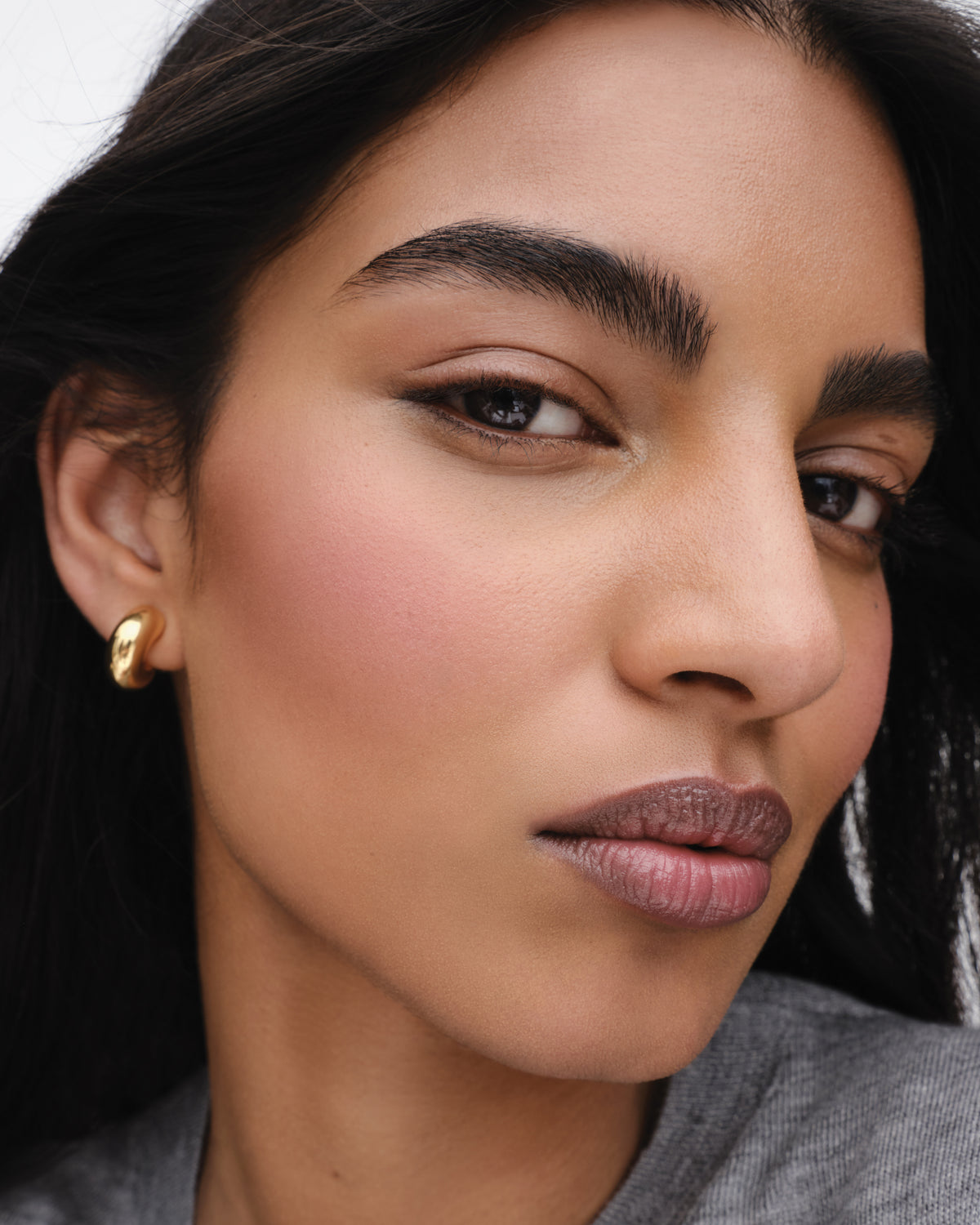 Model wears Baby Cheeks & Face Trace Sculpting Powder Duo in Tulle / Truffle. 